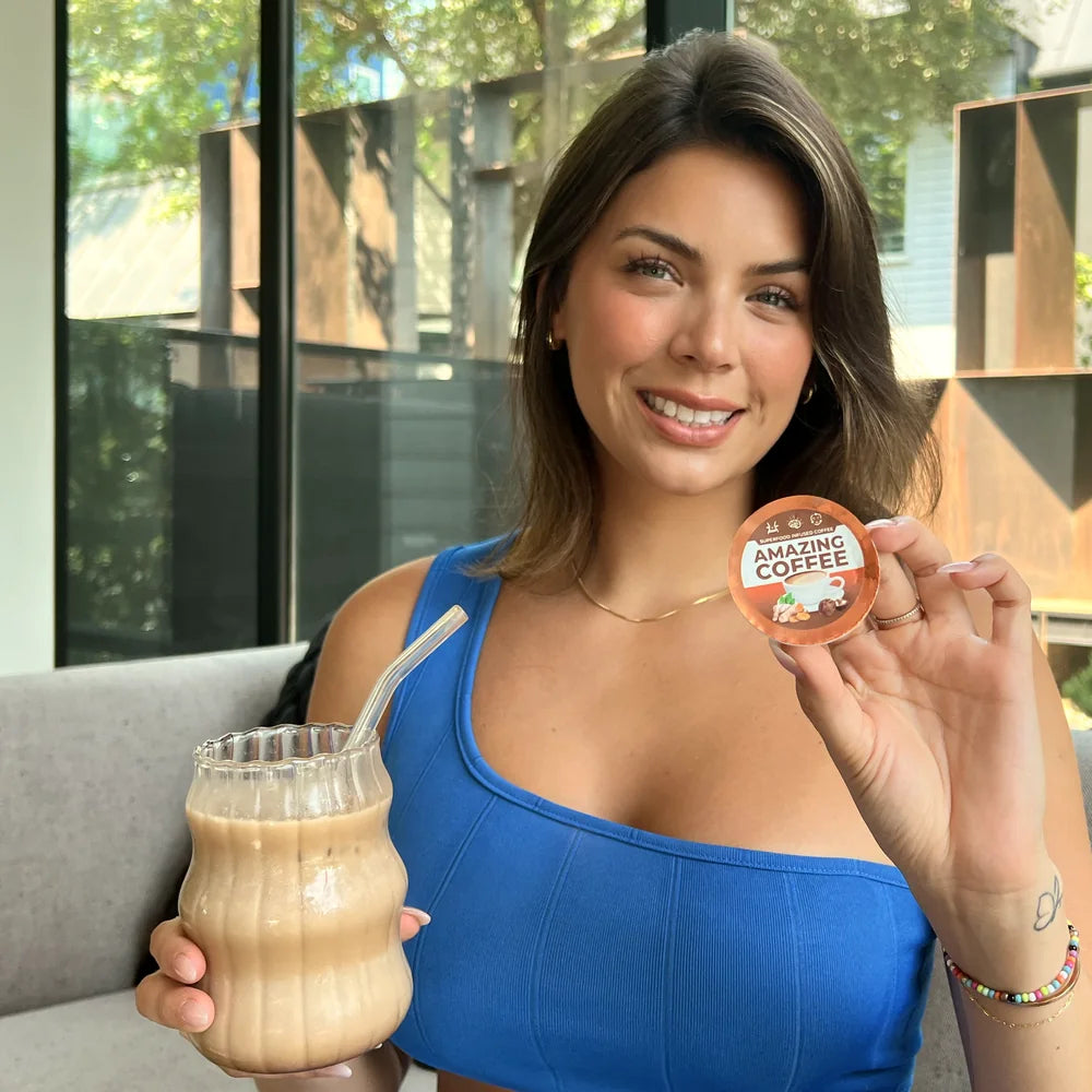 A woman holding an Amazing Coffee pod beside a glass of iced Amazing Coffee